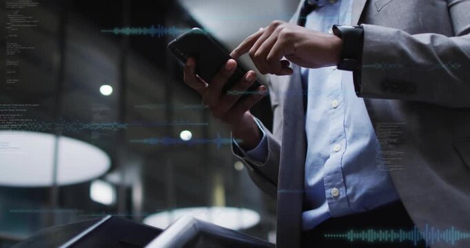 Businessman raising smartphone to reader in lobby, activating data overlays for security access