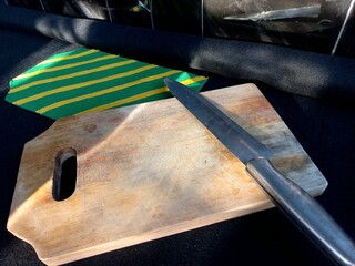 A knife, an old cutting board, and it's fabric base, on a black felt