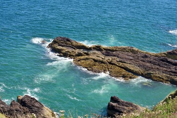 Rocky coastline with turquoise waters and waves crashing, capturing the beauty of the seaside