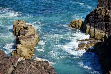 Rocky coastline with turquoise waves crashing against the shore, showcasing natural beauty