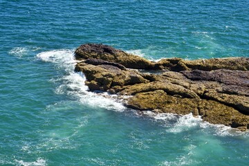 Rocky coastline with waves crashing against the shore in a vibrant blue sea
