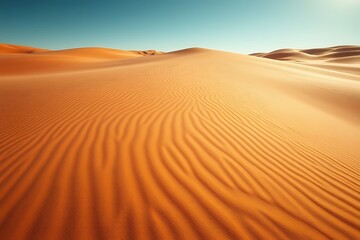 Vast desert landscape with rippled sand dunes under a clear blue sky