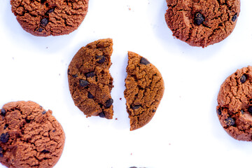 Top view of crunchy chocolate chip cookies with one broken in half on a white background, perfect...