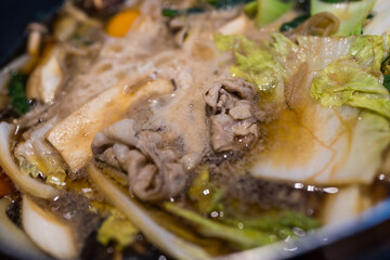 Sukiyaki hot pot simmering with tender beef and vibrant vegetables ready to enjoy. Close up