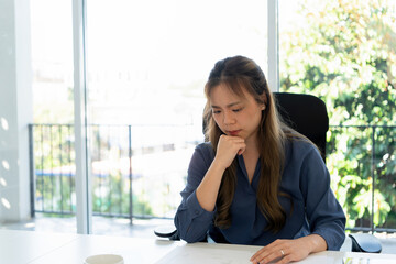 Obraz premium Businesswoman sitting at desk on couch in workplace or at home working on laptop and analyzing data on charts and graphs and writing on papers to make business plan and strategies for company.