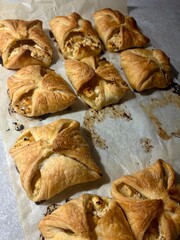 Homemade puff pastry pies with cheese filling on baking paper top view. 