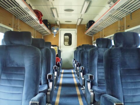A train car with blue seats and a red bag on the floor, train Oruro to Uyuni