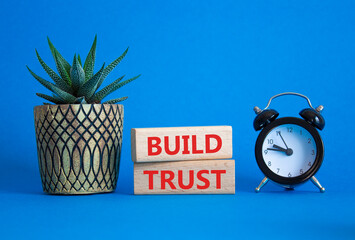 Build trust symbol. Wooden blocks with words Build trust. Beautiful blue background with alarm...