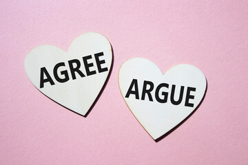 Agree or Argue symbol. Concept word Agree or Argue on wooden hearts. Beautiful pink background. Business and Agree or Argue concept. Copy space