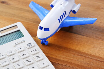 電卓と飛行機 - 高騰する航空券代と、高騰する旅行代金のイメージ
