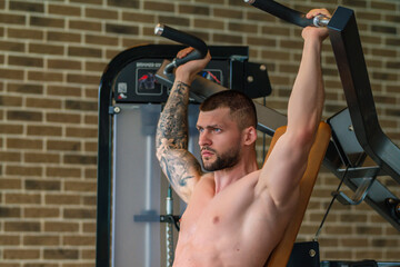 Muscular hunk with posing in gym. Fitness male model near gym equipment. Young muscular man...