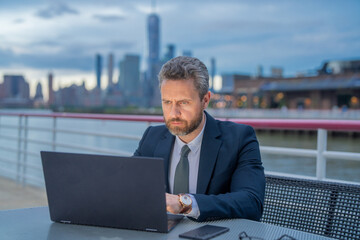 Man freelancer working on laptop in NY near office building outdoors. Business and freelance....