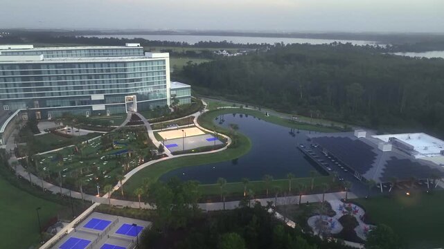 Tennis fields, palm trees, solar panels on roofs and modern company building of KPMG, Orlando. Foggy sunset time in Florida. Aerial tilt up wide shot.