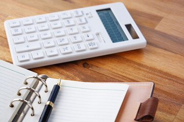 Calculator with opened notebook on table
