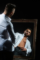 Sexy male model with hot naked body in white shirt. A sexy man in an unbuttoned white shirt on...
