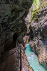 Narrow walkway carved into the cliffside along a turquoise stream inside Partnachklamm Gorge, Garmisch-Partenkirchen, Bavaria. A stunning natural passageway through dramatic alpine rock formations.