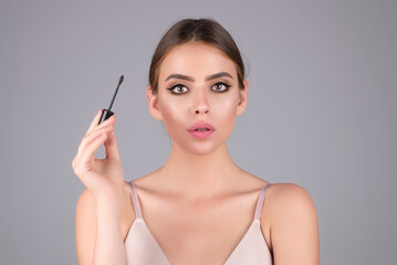 Beautiful woman applies brow gel with brows brush to her eyebrow. Studio portrait of young woman...