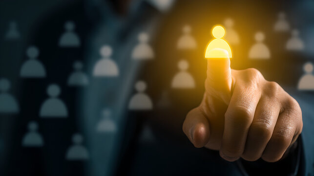 Businessman's hand pointing at a highlighted, glowing human icon, symbolizing the selection of a key person.