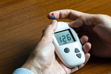 Woman's hands checking diabetes and hyperglycemia with digital blood sugar meter. Healthcare and medical concept
