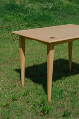 Wooden table on green lawn, ideal for outdoor gatherings or as a nature-inspired centerpiece.