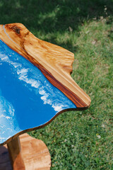 Artistic wood table with epoxy resin ocean effect, outdoors in a green grass lawn, a decorative piece.