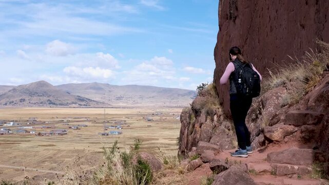 Witness a tourist capturing the incredible panoramic landscape from a high vantage point at the Aramu Muru Portal archaeological site in Peru