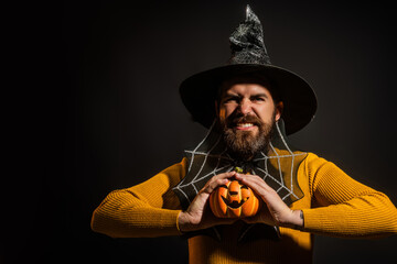 Halloween man with pumpkin. Man in Halloween hat with pumpkin. Trick or treat. Scary hipster man with beard in Halloween hat. Man with witch hat hold pumpkin.