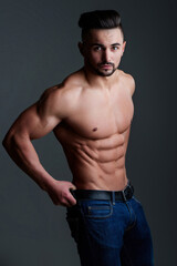 Slim muscular male model at black background. Fitness shirtless guy in posing in studio. Man with...