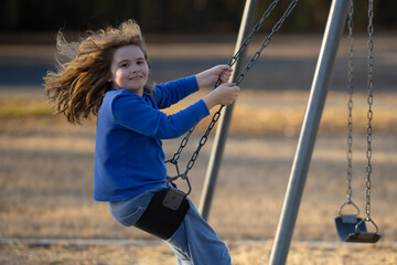 Child enjoying a fun ride on swing. Happy kid on playground. Carefree kid swinging outdoors. Happy...