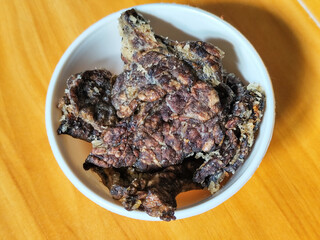 Fried beef lung with flour, has a delicious and delicious taste, served in a white bowl on a wooden table.