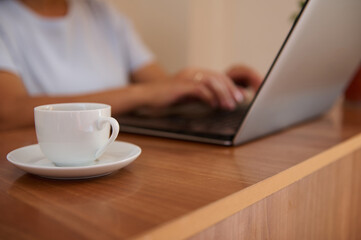 Young Woman Working Remotely on Laptop While Enjoying a Cup of Coffee in Cozy Home Interior