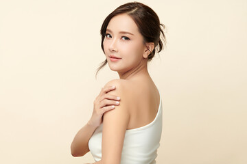 A beautiful young Asian woman with clean, fresh skin against a beige background. Skincare, facial treatment, cosmetology, beauty, and spa. An elegant portrait of an Asian woman.