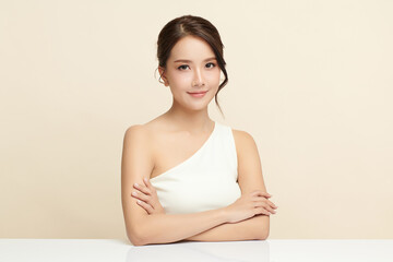 A beautiful young Asian woman with clean, fresh skin against a beige background. Skincare, facial treatment, cosmetology, beauty, and spa. An elegant portrait of an Asian woman.