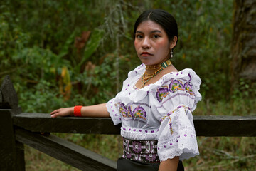 Indigenous woman wearing traditional clothing posing in a forest