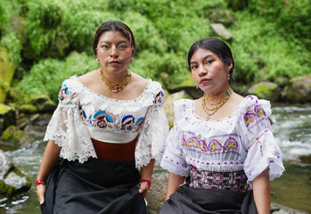 Indigenous women wearing traditional clothes posing by river
