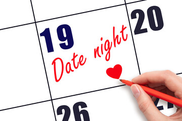 19th day of the month.  Hand writing Date night reminder and drawing a red heart on calendar with...