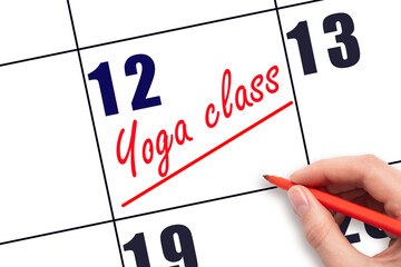 12th day of the month.  Hand writing Yoga class reminder and drawing a line on calendar with red...