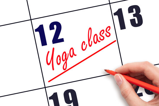 12th day of the month.  Hand writing Yoga class reminder and drawing a line on calendar with red pen on white background. Concept of sport and fitness activity.  Planning and scheduling