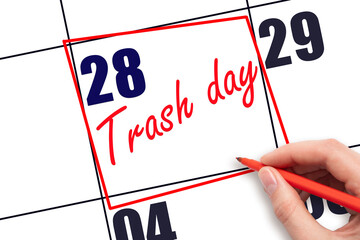 28th day of the month.  Hand writing Trash day reminder and drawing red frame on calendar with red...