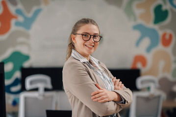 Young businesswoman smiling with crossed arms in modern office
