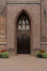 Architectural facade with arched entryway, decorative window, and brickwork with flower planters.