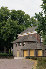 Charming brick building with yellow doors surrounded by lush greenery on a cloudy day. Serene neighborhood.