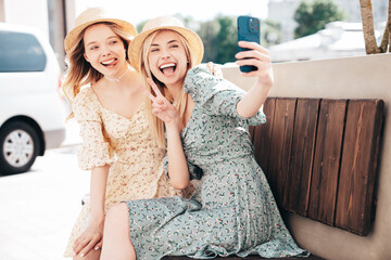 Two young beautiful smiling hipster female in trendy summer dress  clothes. Blond carefree women...