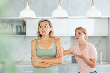 Agitated daughter imploringly asks angry mother for forgiveness. Concept of child rearing,...