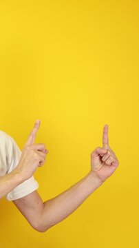 Vertical close-up of two hands pointing at empty yellow background. Ideal for app callouts, UI overlays, ad banners, e-learning modules, product demos, Black Friday and Cyber Monday promotions.