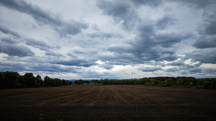 Obraz premium Dark cloudy sky over a plowed field 