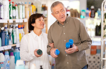 Couple elderly man and woman buyers chooses plastic garbage bags in household chemicals store
