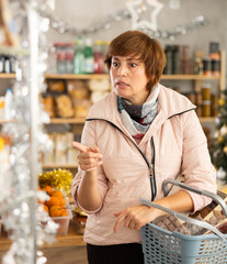 Portrait of modern woman with cart shopping at big supermarket, looking for something. Christmas...