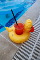 Summer Beach composition with inflatable mini duck with cold drink on the edge of the pool. Fashion party concept.