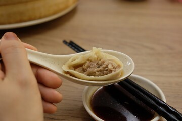 A person is holding a spoonful of food in their hand, which is placed in a bowl